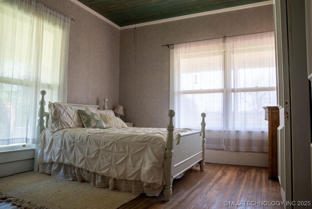bedroom with crown molding, wood finished floors, and multiple windows