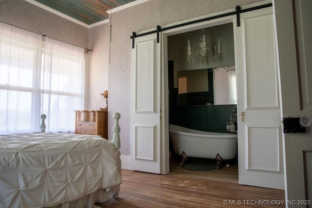 bedroom with wood finished floors, multiple windows, and a barn door