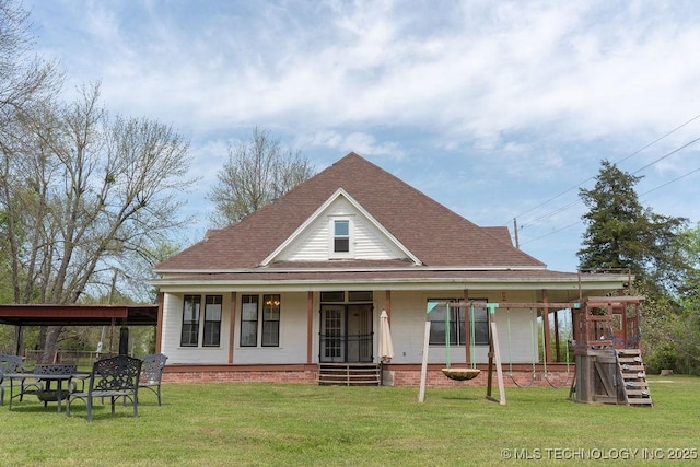 back of property with roof with shingles, a porch, and a lawn