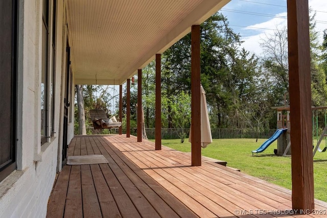 wooden terrace with fence, a lawn, and a playground