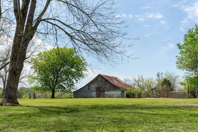 view of yard with a barn, fence, and an outbuilding