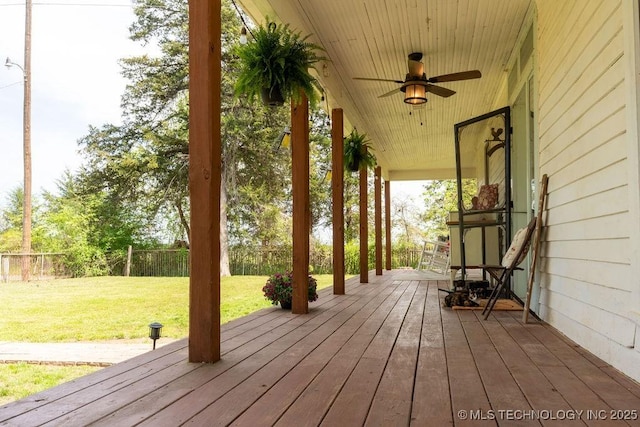deck with a ceiling fan, fence, and a lawn