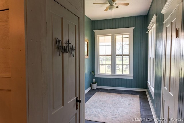 doorway to outside featuring baseboards and a ceiling fan
