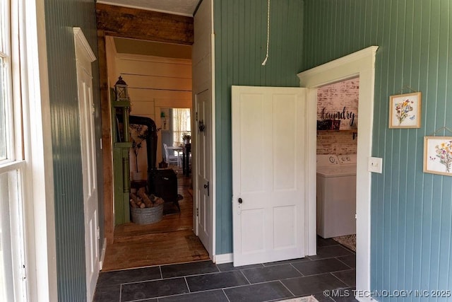 hallway with dark tile patterned flooring and washer / dryer