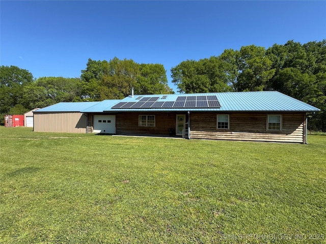 back of property with an attached garage, a lawn, and roof mounted solar panels