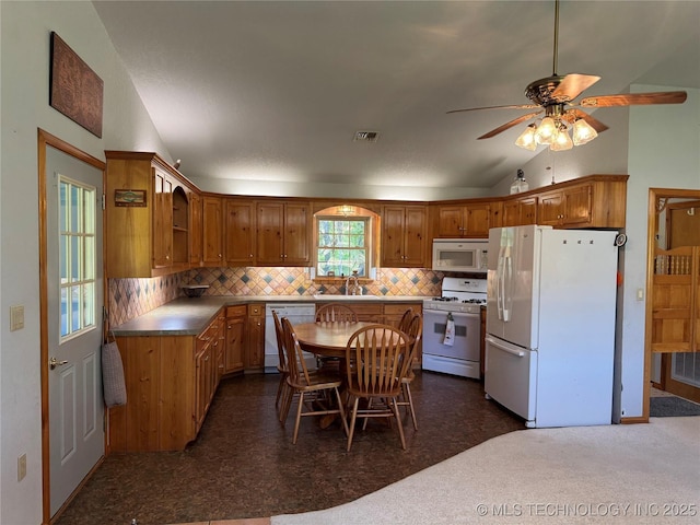 kitchen featuring white appliances, visible vents, a sink, lofted ceiling, and decorative backsplash