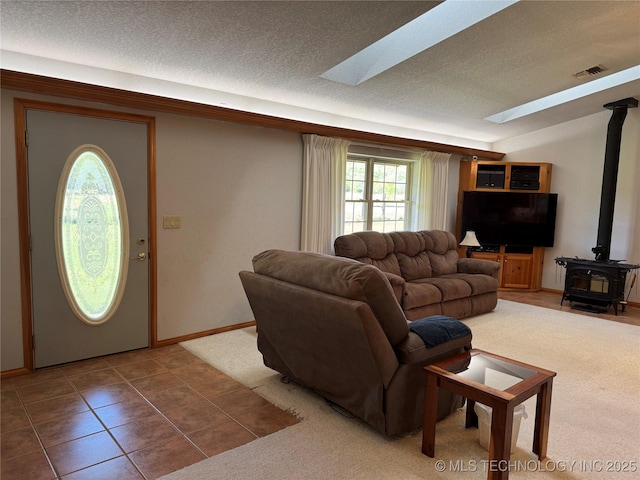 tiled living room with a skylight, a wood stove, plenty of natural light, and a textured ceiling
