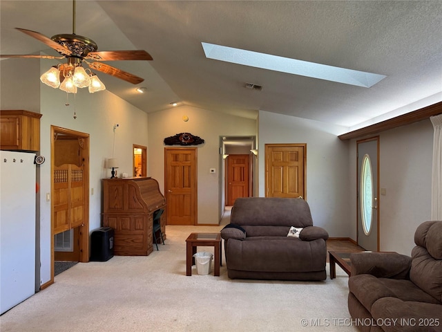 living room with visible vents, a ceiling fan, light colored carpet, and lofted ceiling with skylight