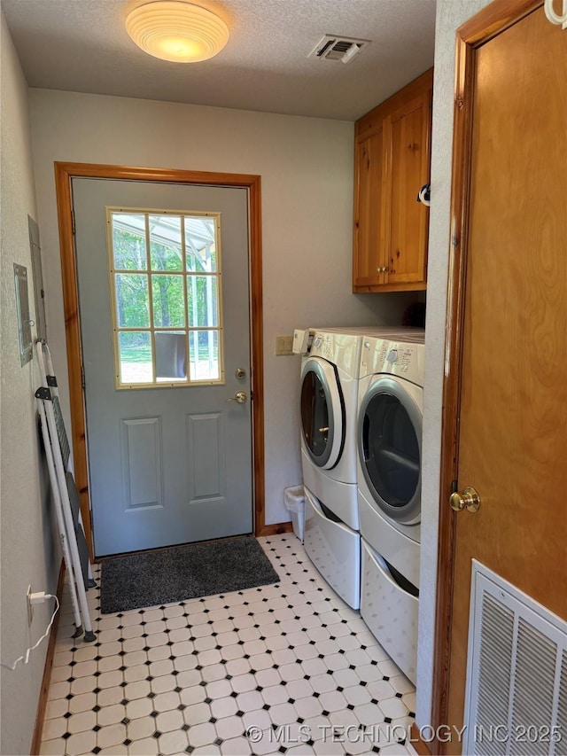 washroom with washing machine and dryer, baseboards, cabinet space, and visible vents