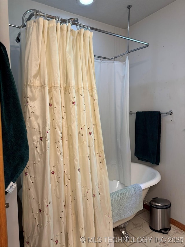 bathroom featuring shower / bath combo with shower curtain, baseboards, and tile patterned flooring