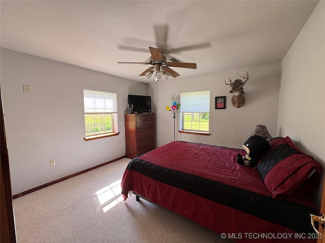 carpeted bedroom featuring baseboards, ceiling fan, and a textured ceiling