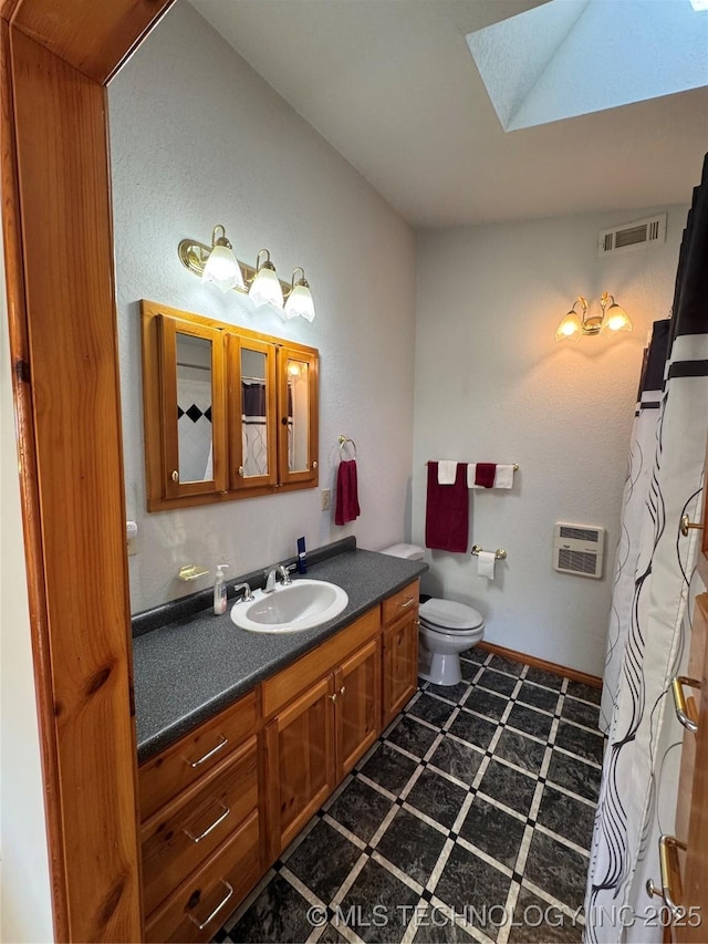 bathroom with visible vents, tile patterned floors, toilet, vanity, and a skylight