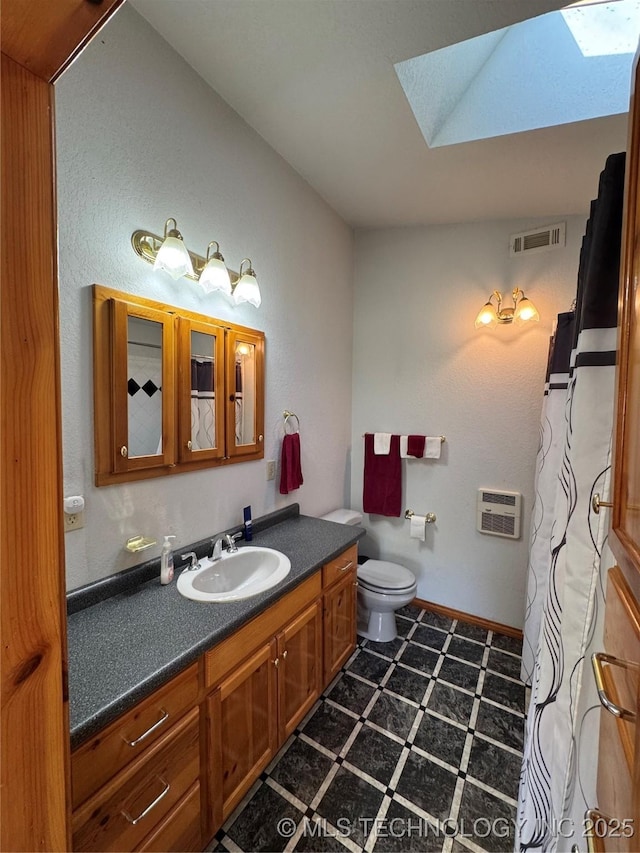 full bath featuring vanity, visible vents, toilet, a skylight, and an AC wall unit