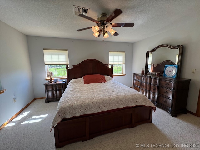 bedroom with light carpet, visible vents, a textured ceiling, and a ceiling fan
