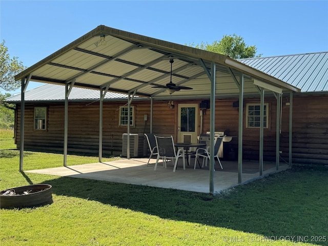 rear view of house with a lawn, a patio, metal roof, faux log siding, and central AC unit