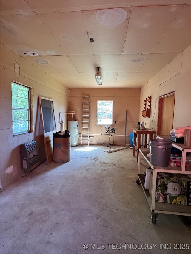 interior space featuring heating unit, unfinished concrete flooring, and water heater