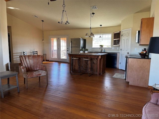 kitchen featuring visible vents, a center island, black dishwasher, freestanding refrigerator, and dark wood-style floors