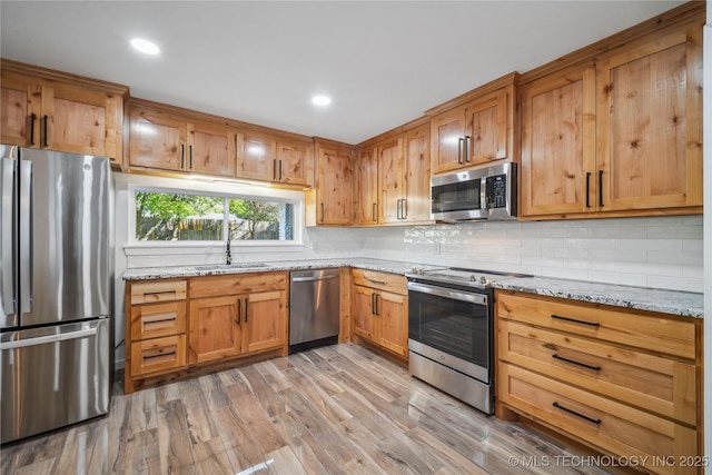 2615 E 59th St, Tulsa, OK 74105 - kitchen with decorative backsplash, light wood-style floors, light stone counters, a sink, and stainless steel appliances