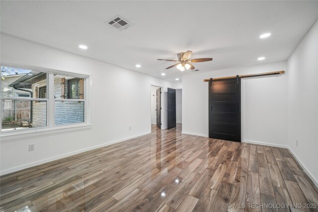 2615 E 59th St, Tulsa, OK 74105 - unfurnished bedroom with visible vents, wood finished floors, a barn door, baseboards, and recessed lighting