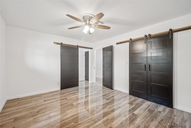 2615 E 59th St, Tulsa, OK 74105 - unfurnished bedroom featuring baseboards, a barn door, and light wood finished floors