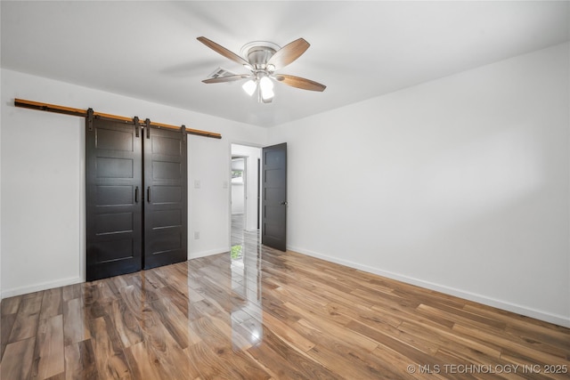 2615 E 59th St, Tulsa, OK 74105 - unfurnished bedroom featuring baseboards, a barn door, ceiling fan, and wood finished floors