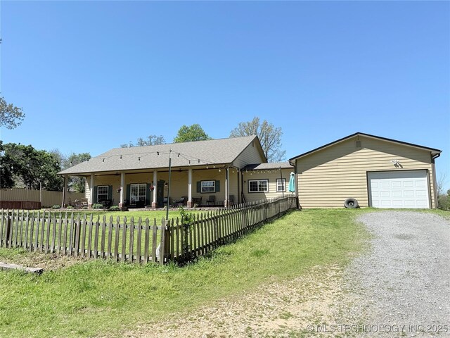 rear view of house featuring gravel driveway, a lawn, and a fenced front yard