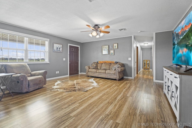 9720 S 4475th Rd, Miami, OK 74354 - living area with a textured ceiling, a ceiling fan, visible vents, wood finished floors, and baseboards