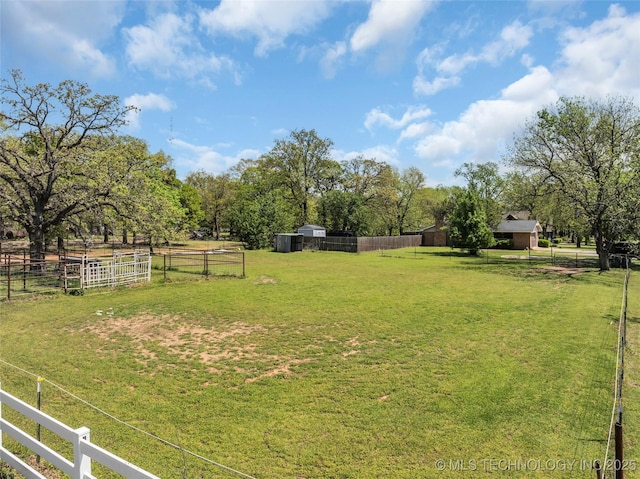 view of yard featuring an outdoor structure, fence, and a rural view