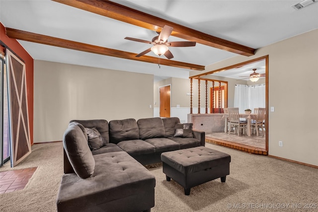 living room featuring carpet, a ceiling fan, visible vents, baseboards, and beam ceiling