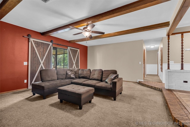 carpeted living area featuring a barn door, beamed ceiling, and ceiling fan