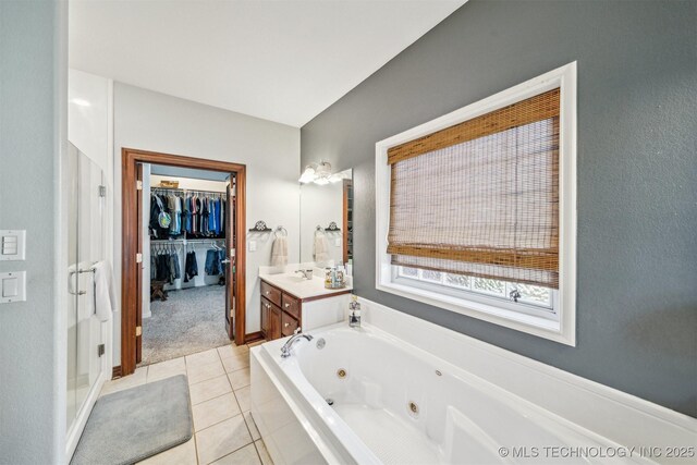 bathroom featuring a walk in closet, tile patterned flooring, a jetted tub, and vanity