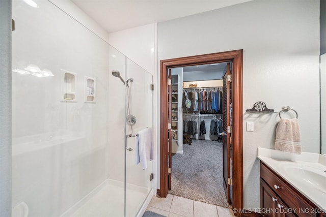 full bathroom with a spacious closet, tile patterned floors, vanity, and a stall shower