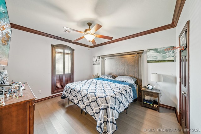 bedroom with wood finished floors, baseboards, and ornamental molding