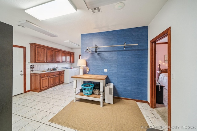 kitchen with light tile patterned floors, independent washer and dryer, visible vents, a sink, and light countertops