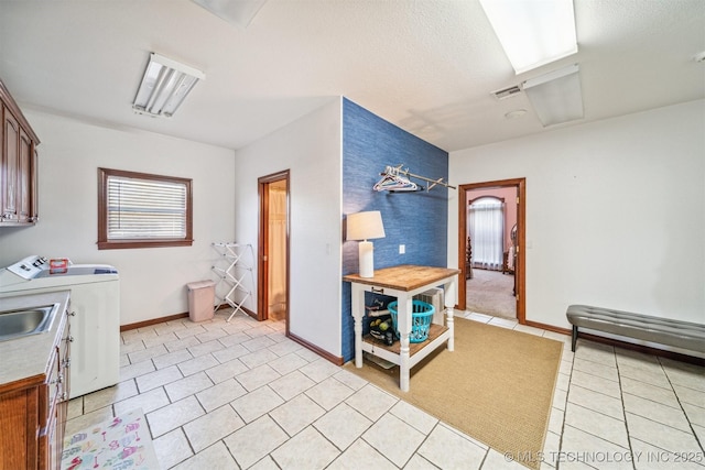 washroom featuring separate washer and dryer, visible vents, light tile patterned flooring, baseboards, and cabinet space