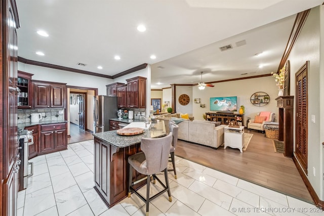 kitchen featuring a breakfast bar, ornamental molding, open floor plan, stainless steel appliances, and marble finish floor
