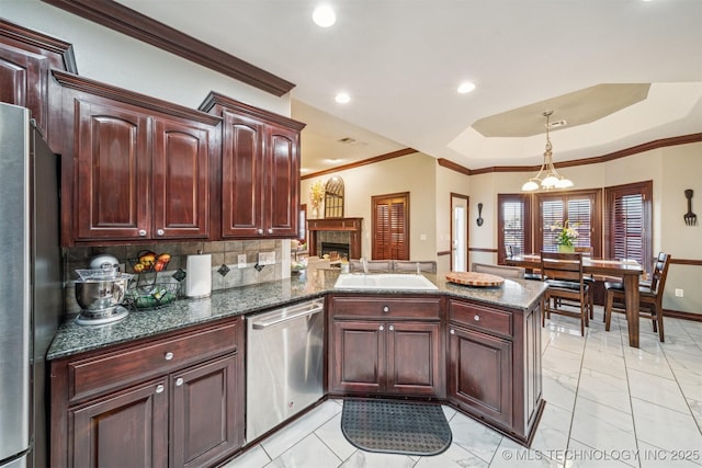 kitchen with crown molding, a peninsula, appliances with stainless steel finishes, and a sink