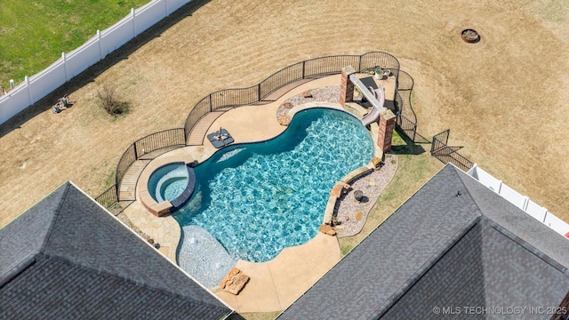 view of pool with a fenced backyard and a pool with connected hot tub