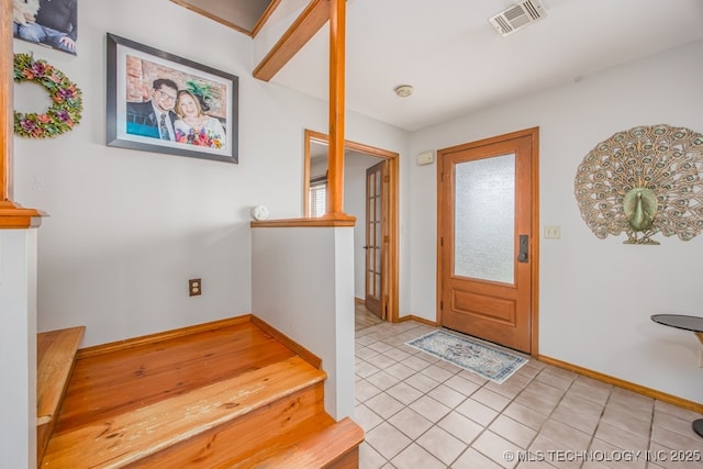 foyer featuring light tile patterned floors, baseboards, and visible vents