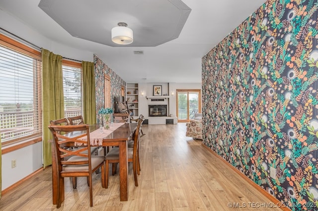 dining room with wood finished floors, baseboards, a glass covered fireplace, and visible vents