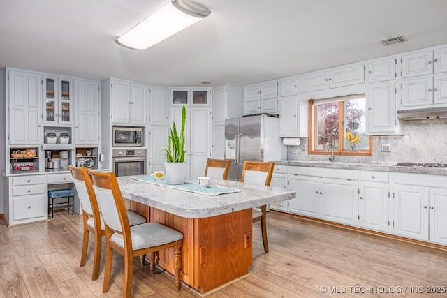 kitchen featuring white cabinets, visible vents, a kitchen bar, and appliances with stainless steel finishes