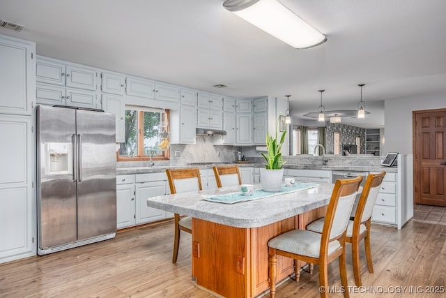 kitchen featuring a wealth of natural light, a peninsula, light wood-style flooring, and appliances with stainless steel finishes