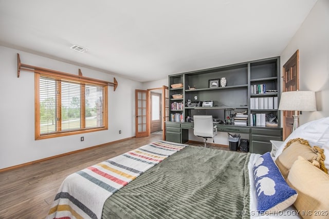 bedroom with visible vents, baseboards, french doors, and wood finished floors
