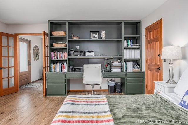 office with built in study area, french doors, and wood finished floors