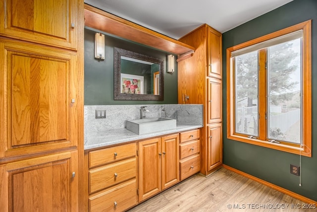 bathroom with decorative backsplash, wood finished floors, vanity, and baseboards