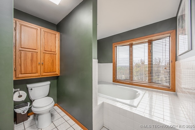 bathroom with a bath, tile patterned floors, toilet, and baseboards