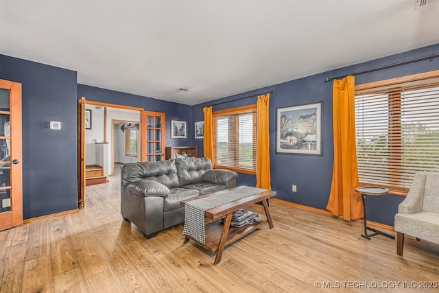 living area featuring visible vents, light wood-type flooring, and baseboards