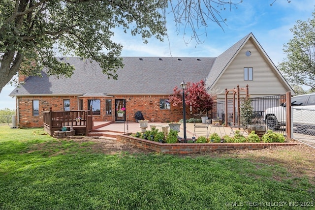 rear view of property featuring a yard, a shingled roof, fence, and brick siding
