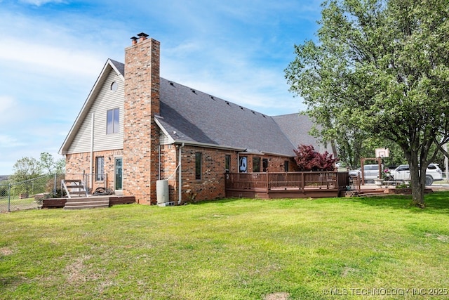 back of property with a yard, a wooden deck, fence, and brick siding