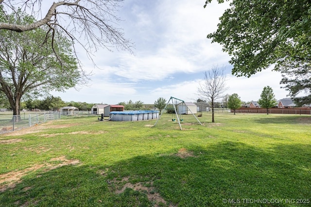 view of yard featuring a fenced backyard, a fenced in pool, and a playground